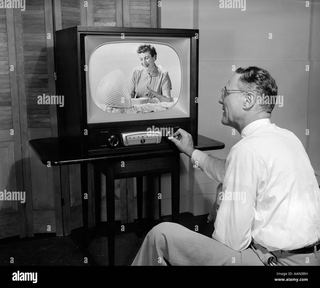 1950s-man-tuning-television-to-a-picture-of-woman-looking-into-bassinet-AAN0RH.jpg