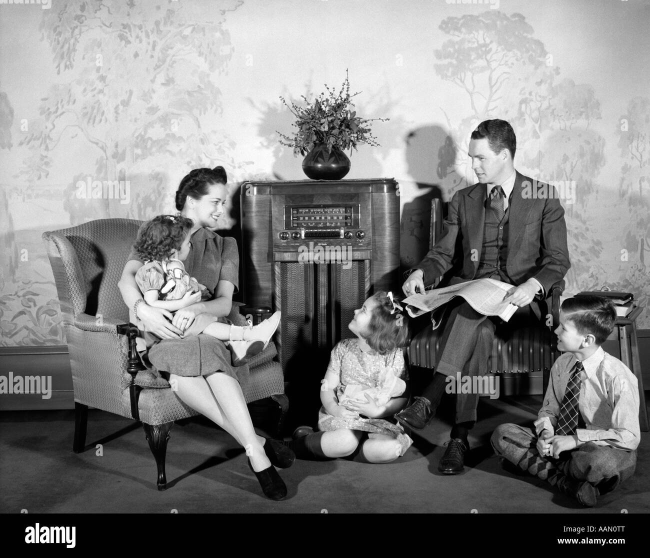1940s FAMILY MAN FATHER WOMAN MOTHER BOY SON TWO GIRLS DAUGHTERS SITTING TOGETHER LISTENING TO RADIO Stock Photo