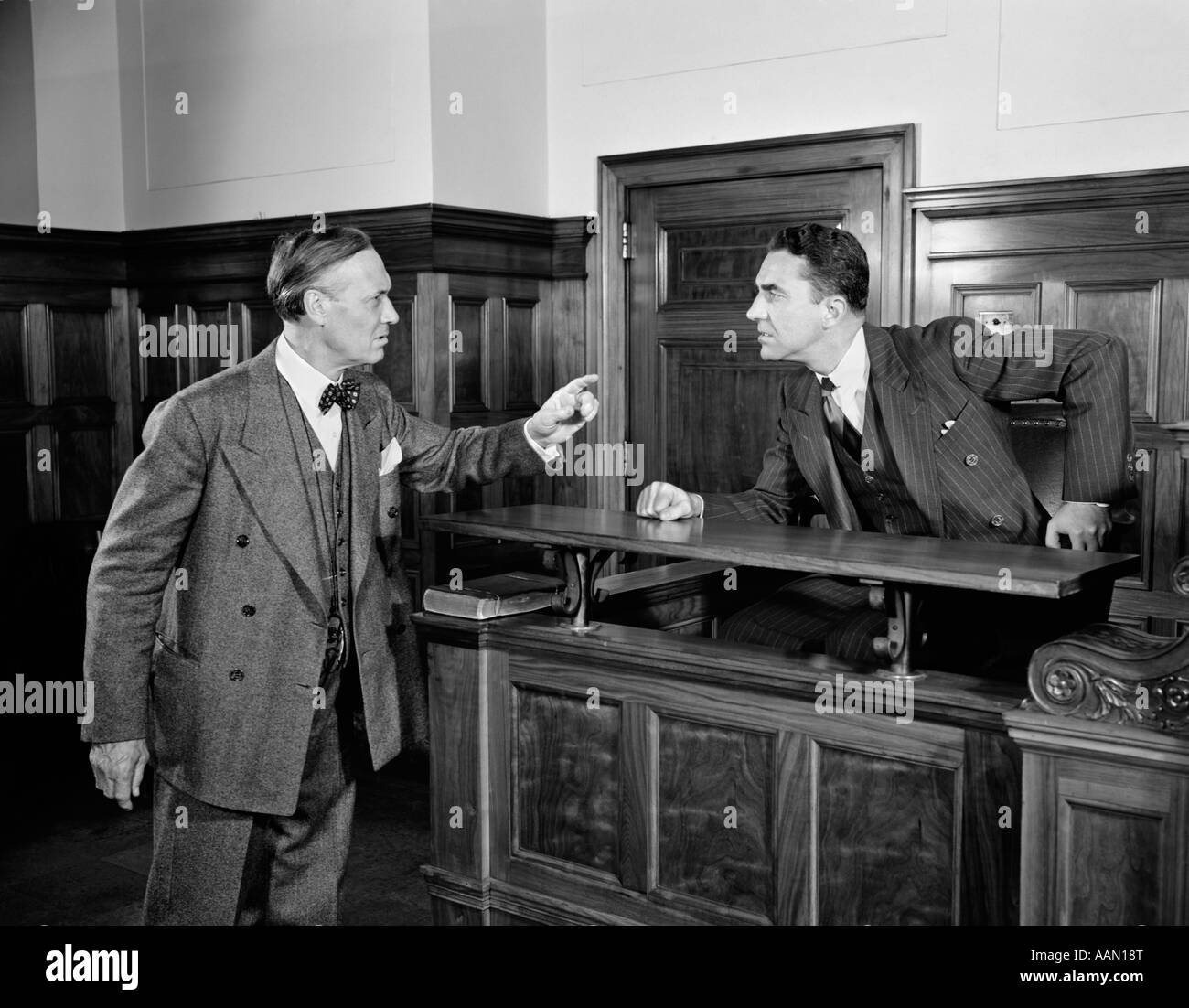 1940s 1950s 2 MEN ATTORNEY LAWYER POINT ARGUE CASE BEFORE JUDGE LAW COURTROOM BENCH LEGAL Stock Photo