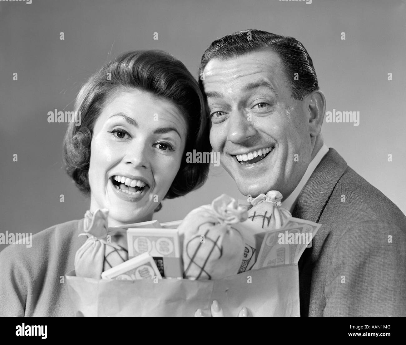 1960s MAN WOMAN COUPLE MONEY BAGS CASH HAPPY Stock Photo