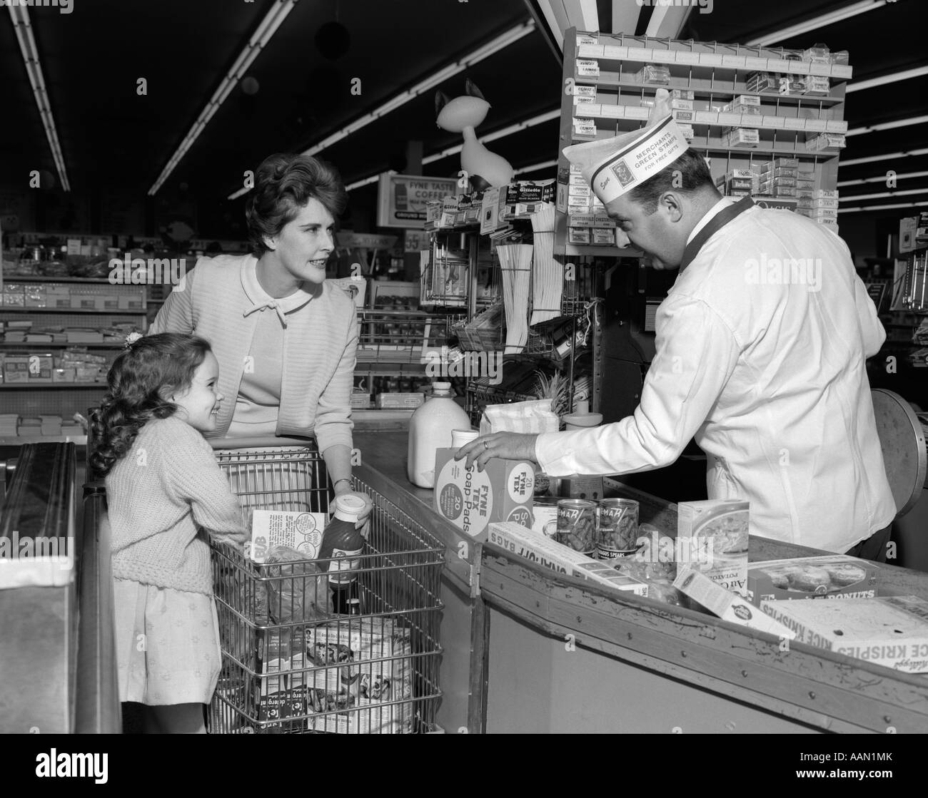 1960s MOTHER DAUGHTER UNLOAD GROCERY CART AT SUPERMARKET CHECKOUT