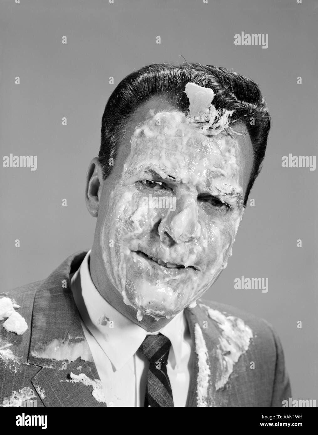 1960s PORTRAIT MAN COVERED IN MERINGUE SHAVING CREAM PIE IN THE FACE FUNNY ANGRY EXPRESSION Stock Photo