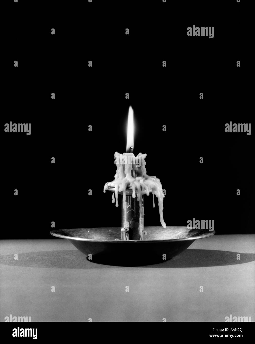 STILL LIFE OF LIT CANDLE BURNED ALMOST ALL THE WAY DOWN DRIPPING WAX Stock Photo