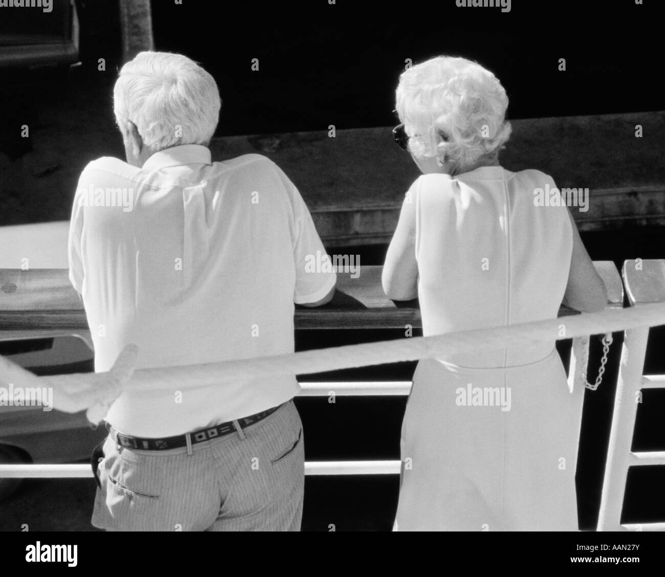 1970s REAR VIEW OF ELDERLY COUPLE LOOKING OVER DECK OF CRUISE SHIP Stock Photo