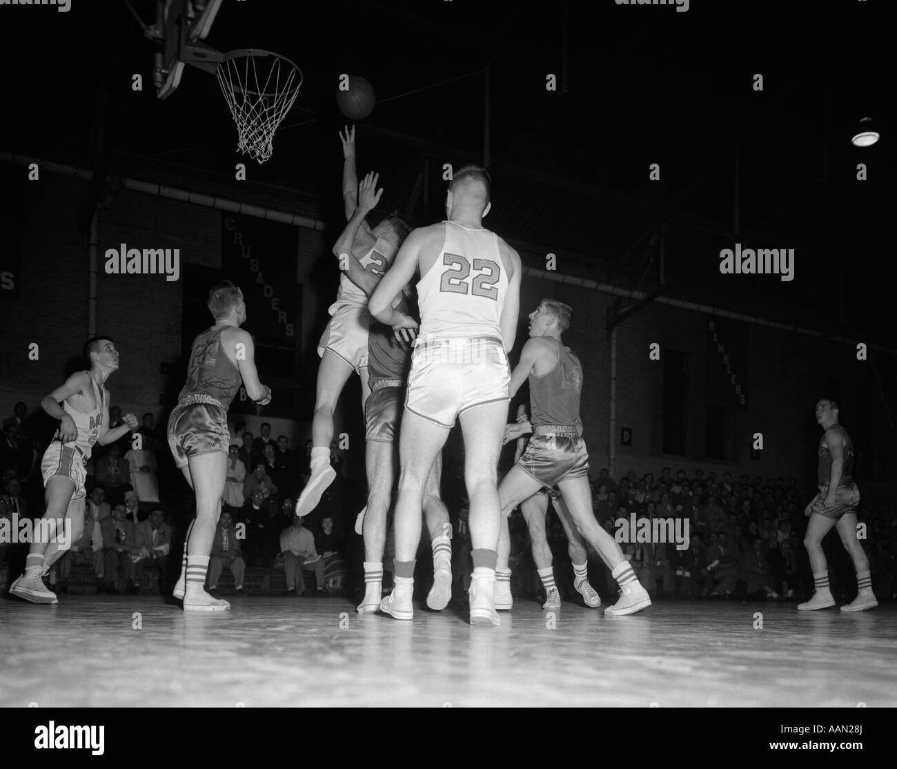 1950s BOYS' BASKETBALL GAME INDOORS BOY JUMPING Stock Photo