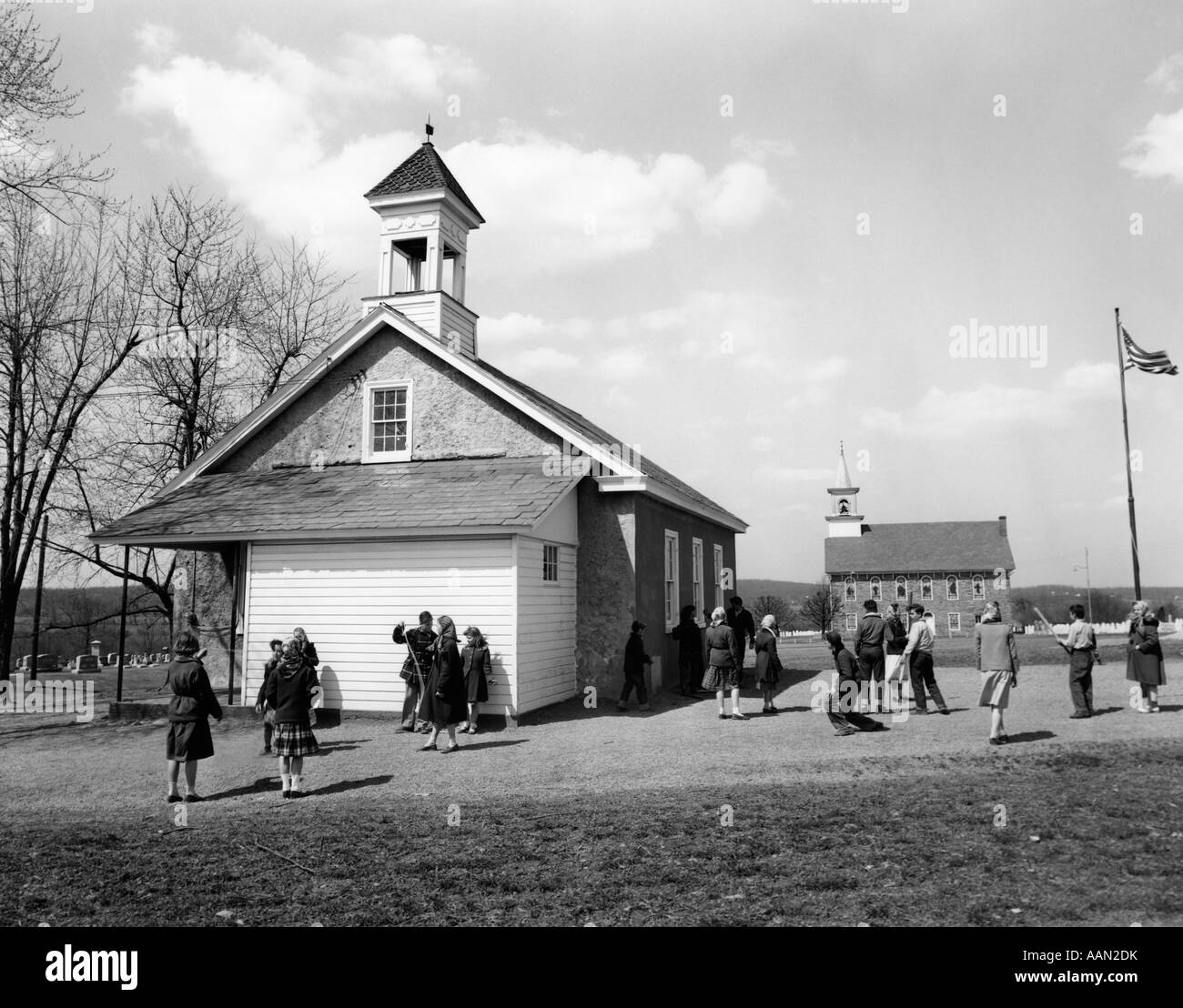 1950s GRADE SCHOOL CHILDREN AT RECESS OUTSIDE OF RURAL ONE-ROOM SCHOOLHOUSE Stock Photo