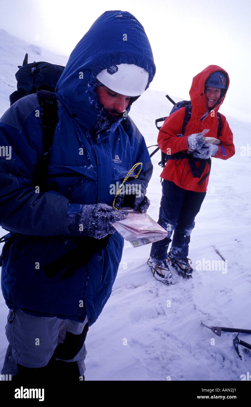 Two walkers look at maps in the cairngorms mountains in Scotland, United Kingdom Stock Photo