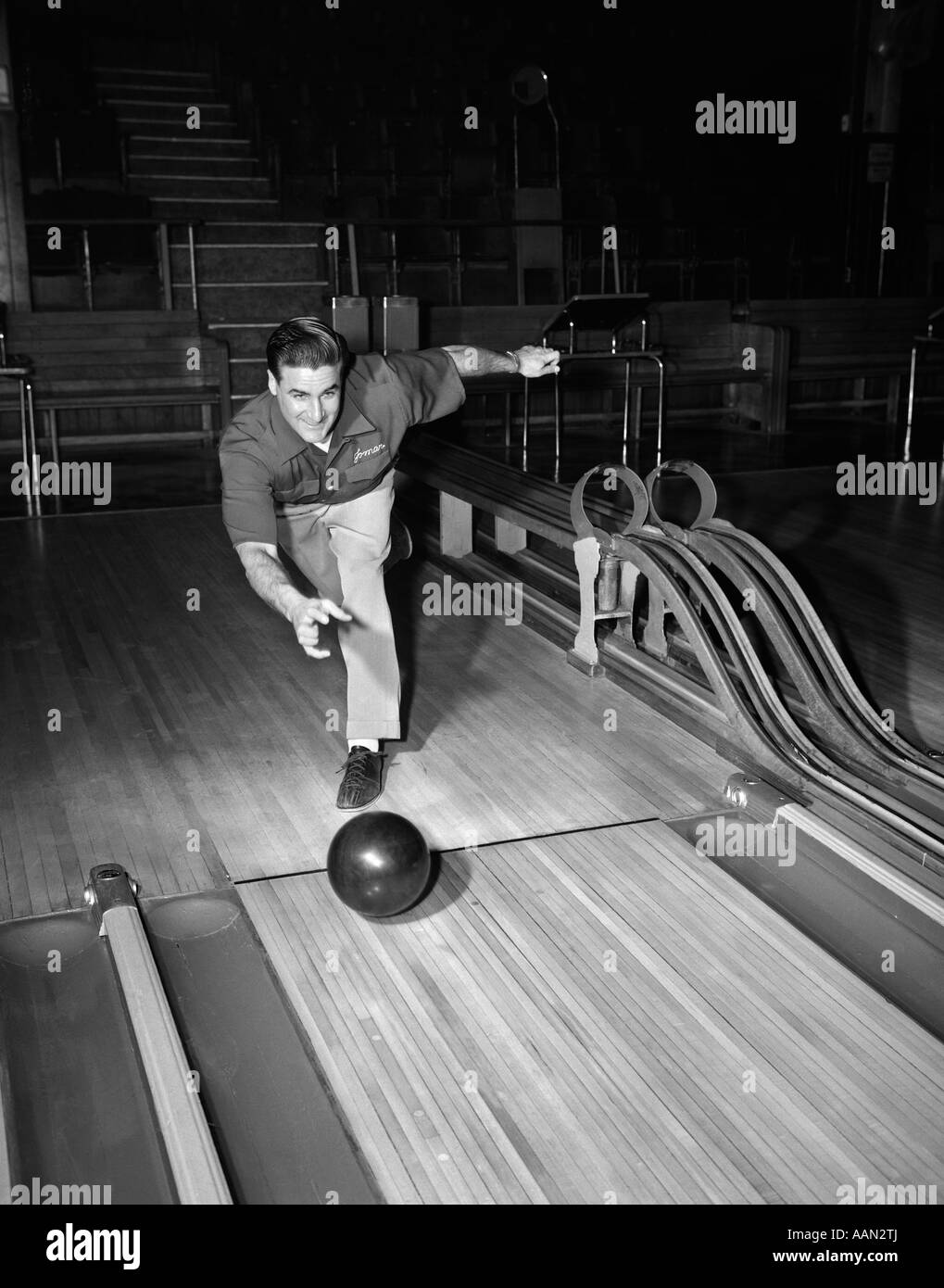 1940s 1950s MAN THROWING BOWLING BALL DOWN ALLEY Stock Photo