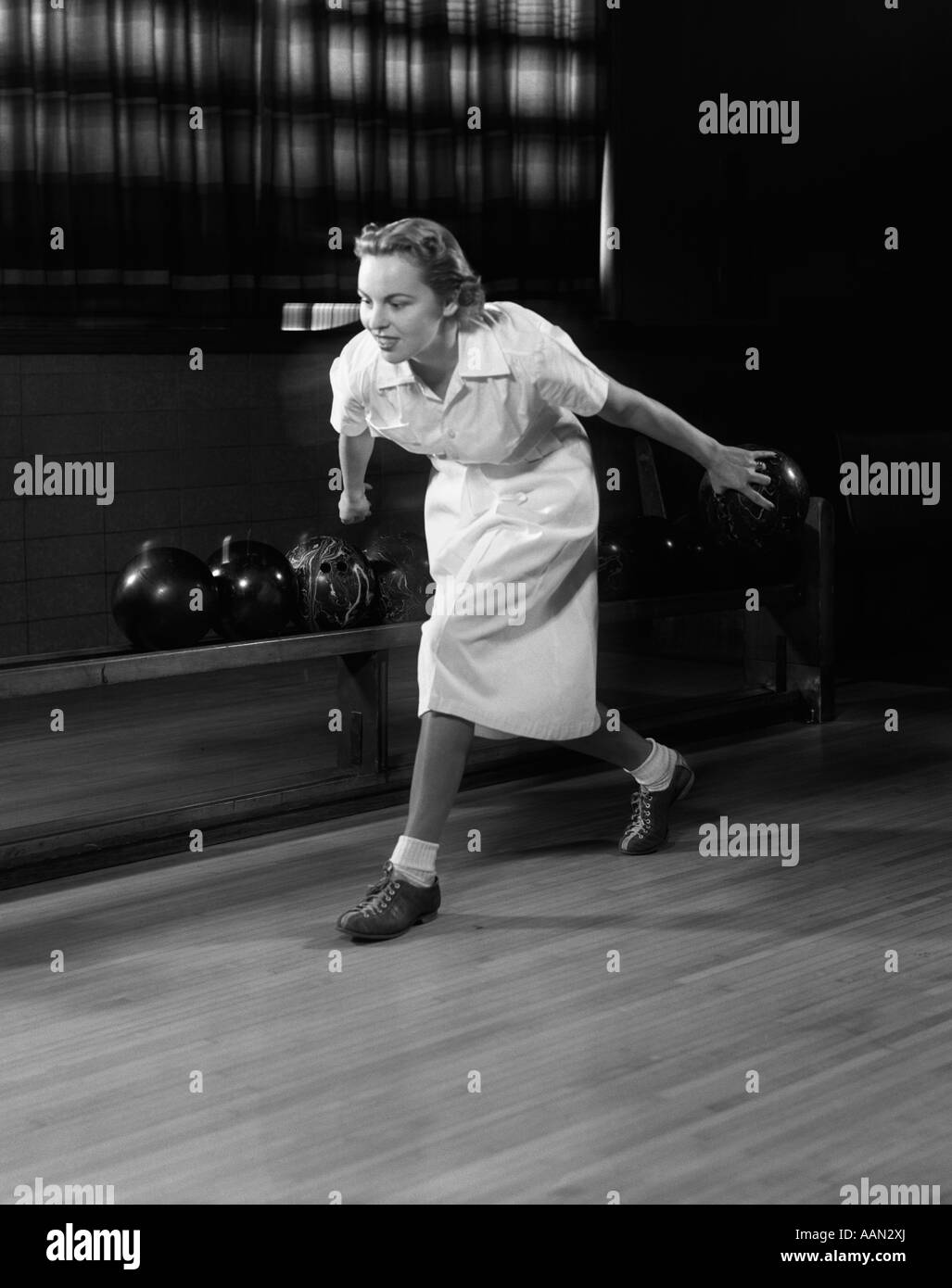 1950s WOMAN BOWLING ABOUT TO RELEASE BOWLING BALL DOWN ALLEY Stock Photo