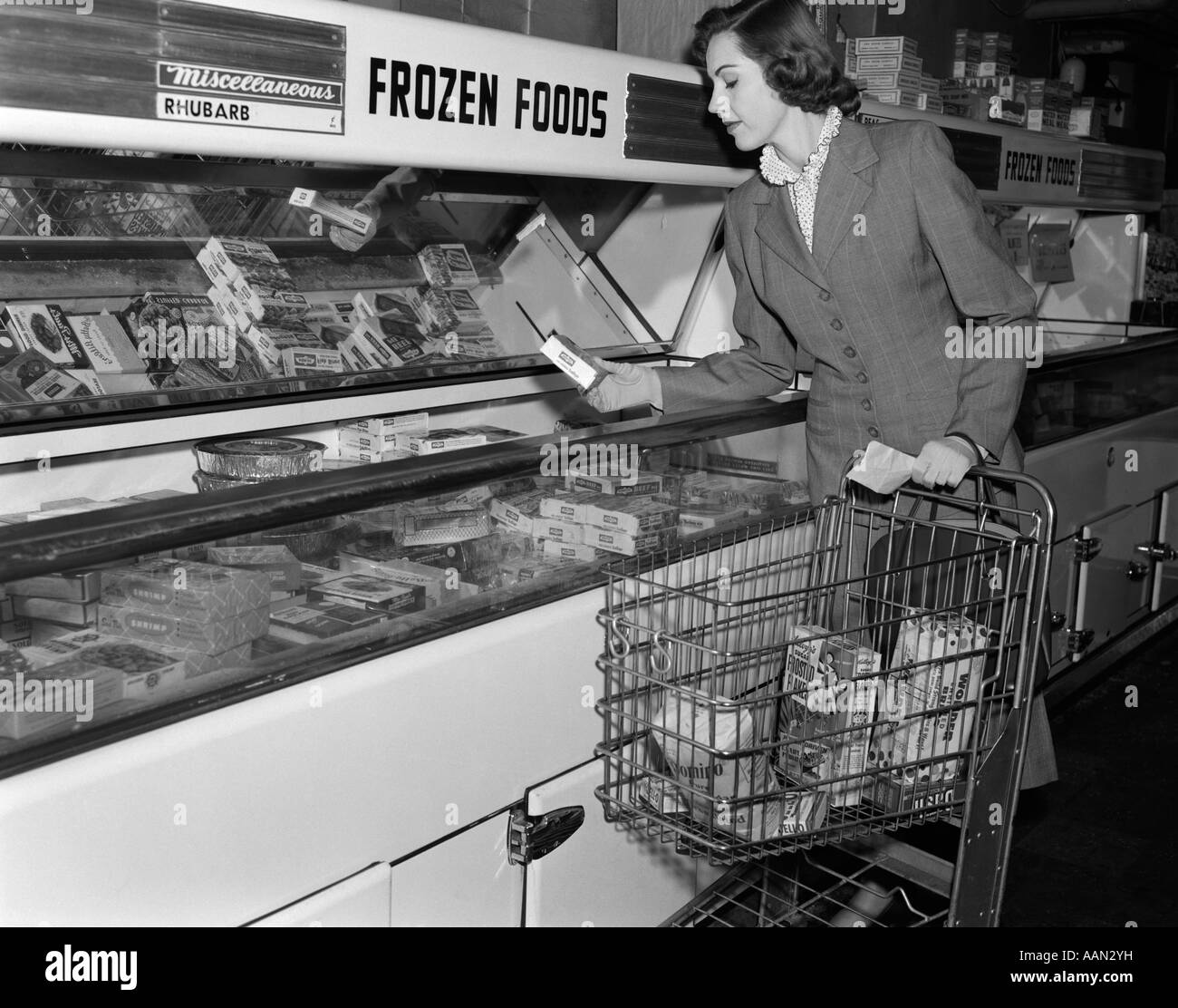 1950s WOMAN SHOPPING FROZEN FOOD SECTION OF GROCERY STORE Stock Photo