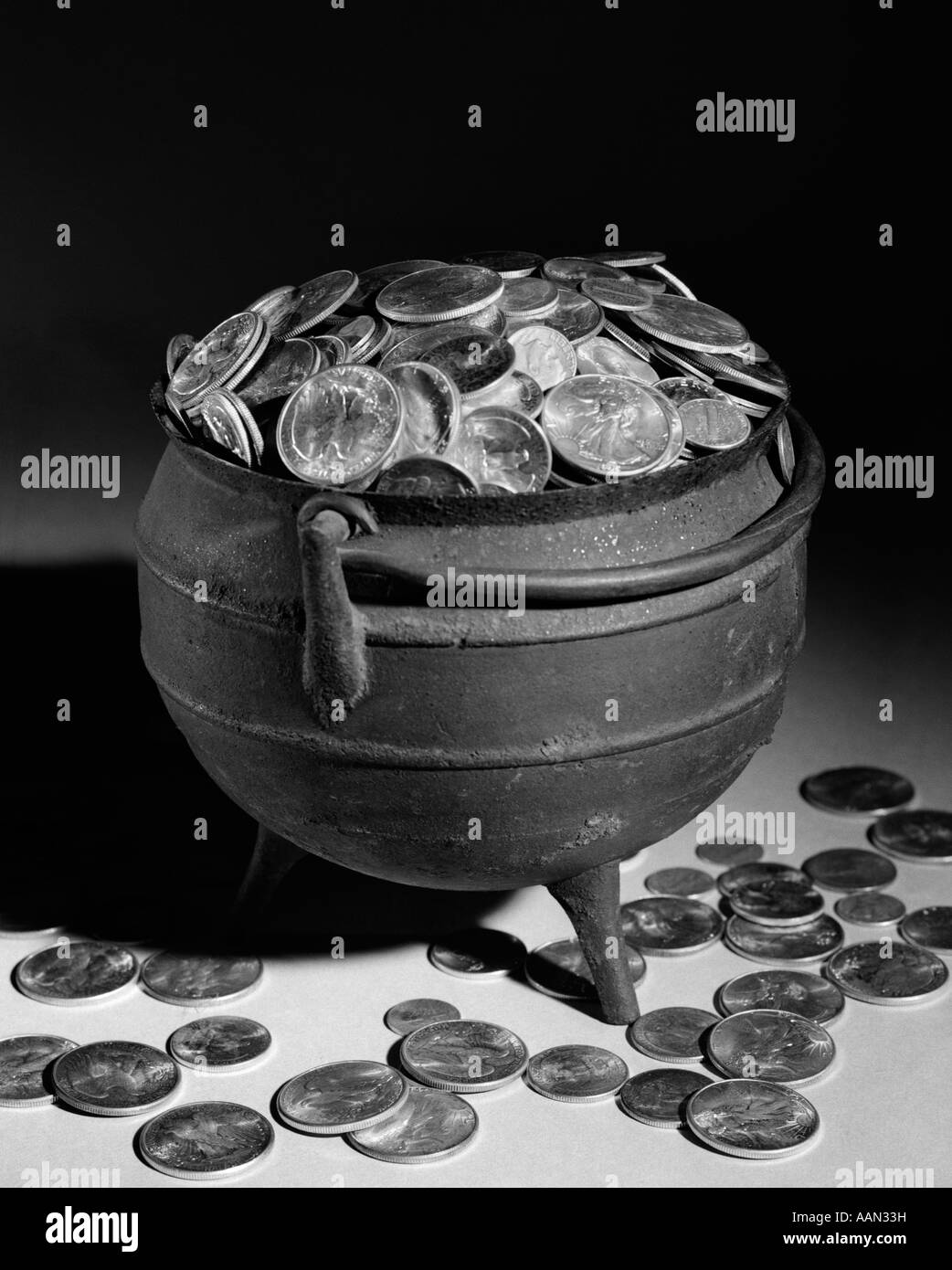 1950s IRON POT OVERFLOWING WITH COINS Stock Photo