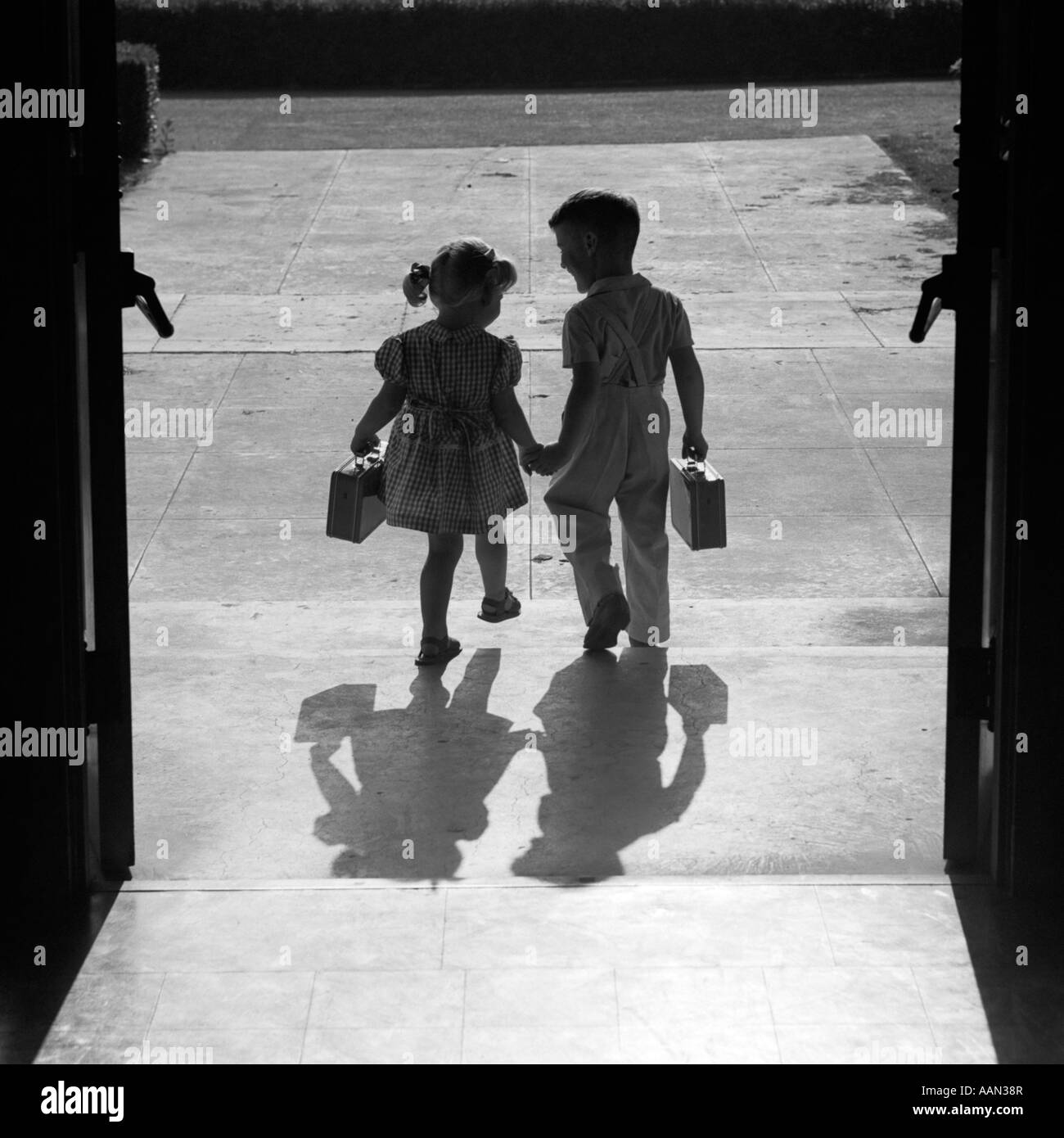 1950s Silhouetted Boy Girl Holding Hands Leaving School Doors Going Home End Of Day Shadows Afternoon Friends Friendship Stock Photo Alamy 1950s Silhouetted Boy Girl Holding Hands Leaving School Doors Going Home End Of Day Shadows Afternoon Friends Friendship Stock Photo Alamy