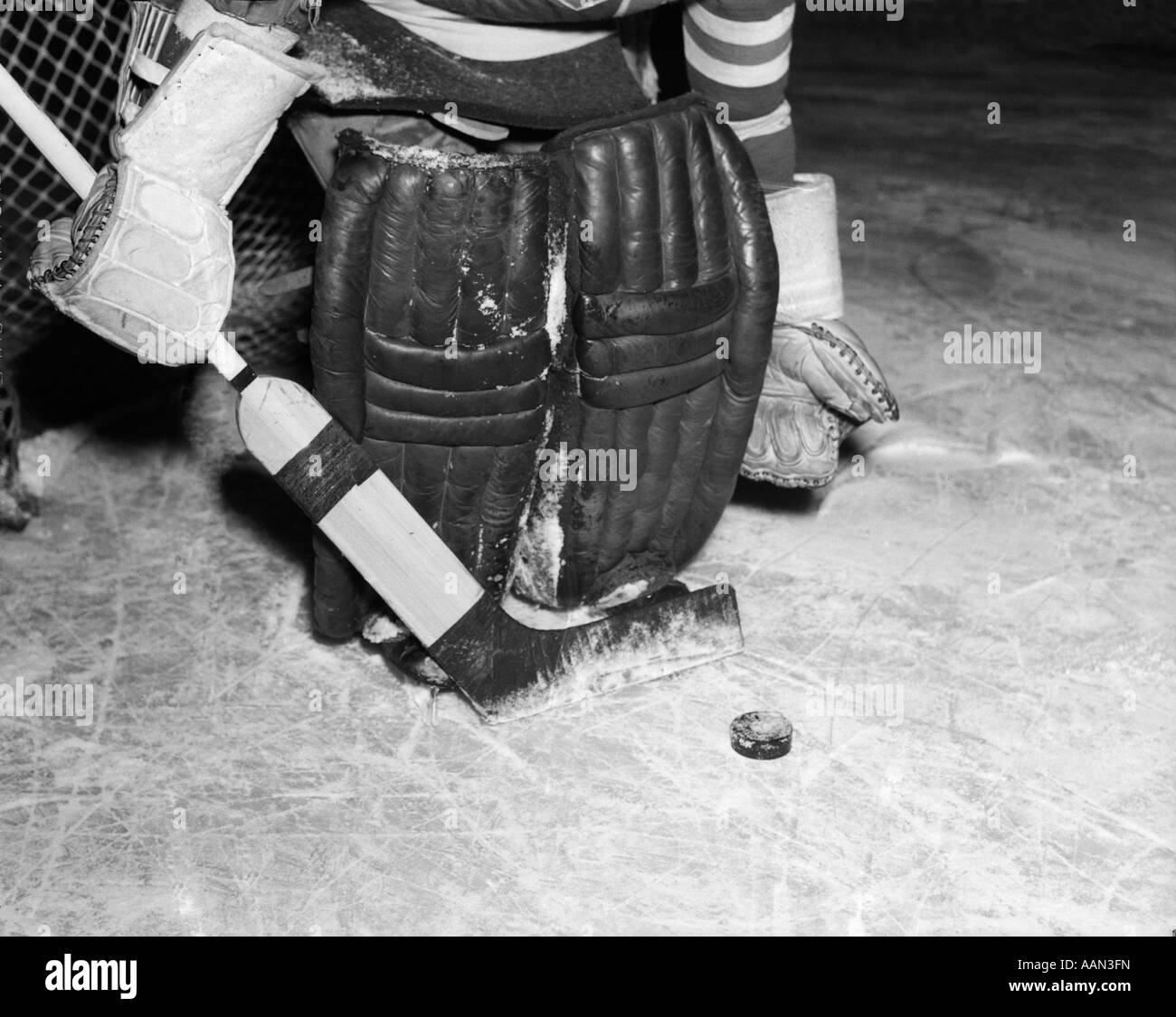 1940s 1950s CLOSE-UP OF PADDED GOALIE SHOWN WAIST-DOWN HOLDING STICK WITH PUCK IN FRONT OF HIM Stock Photo