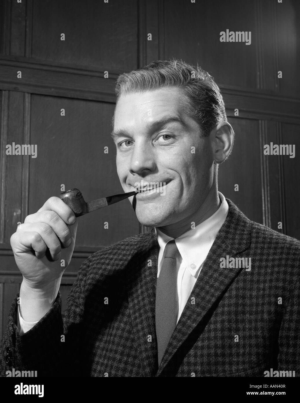 1960s 1950s PORTRAIT OF MAN IN TWEED JACKET SMOKING PIPE SMILING LOOKING AT CAMERA Stock Photo