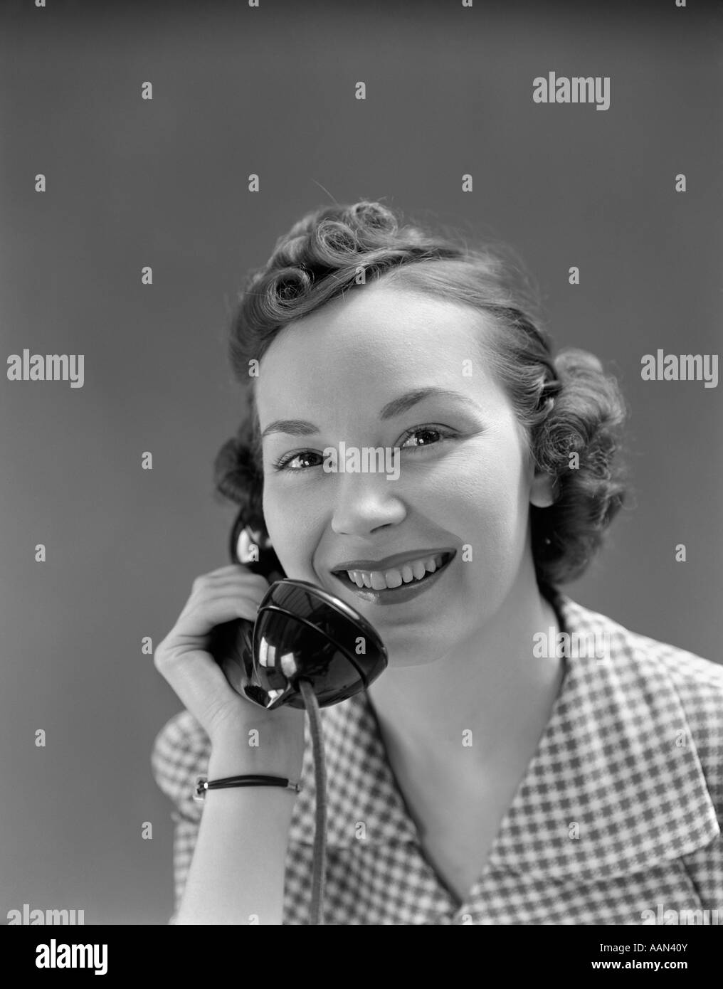 1930s 1940s WOMAN SMILING TALKING ON TELEPHONE LOOKING AT CAMERA Stock Photo