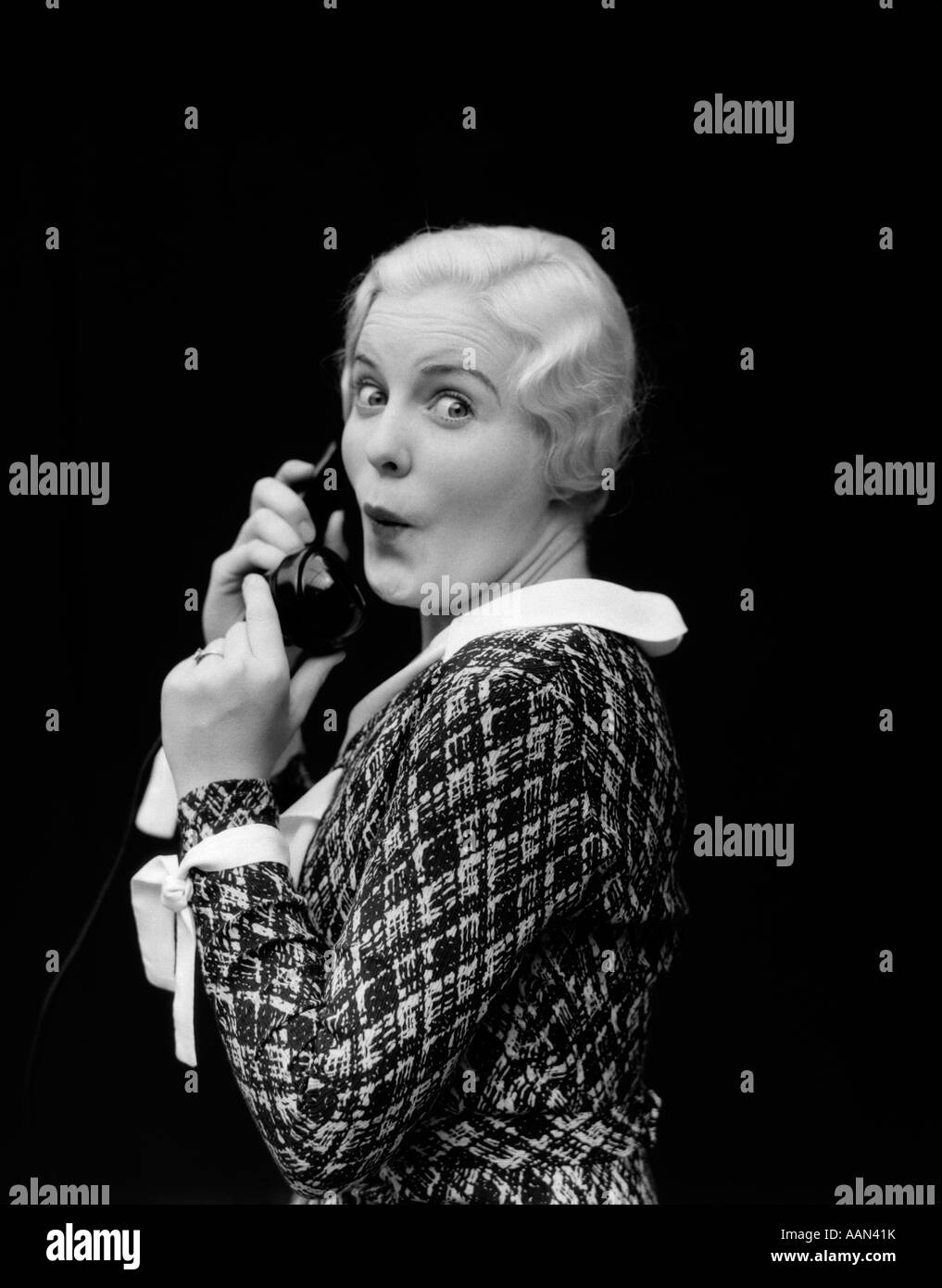 1930s WOMAN TALKING ON TELEPHONE SURPRISED EXPRESSION ON FACE LOOKING AT CAMERA Stock Photo