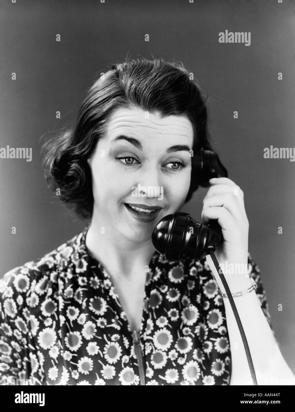 1940s WOMAN SUNFLOWER PRINT DRESS TALKING ON TELEPHONE SMILING Stock Photo