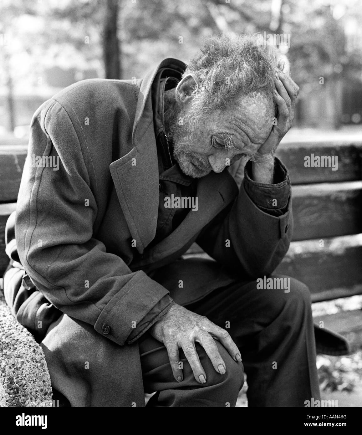 1960s 1970s DESTITUTE ELDERLY MAN SITTING ON PARK BENCH WITH HEAD IN HANDS OUTDOOR Stock Photo