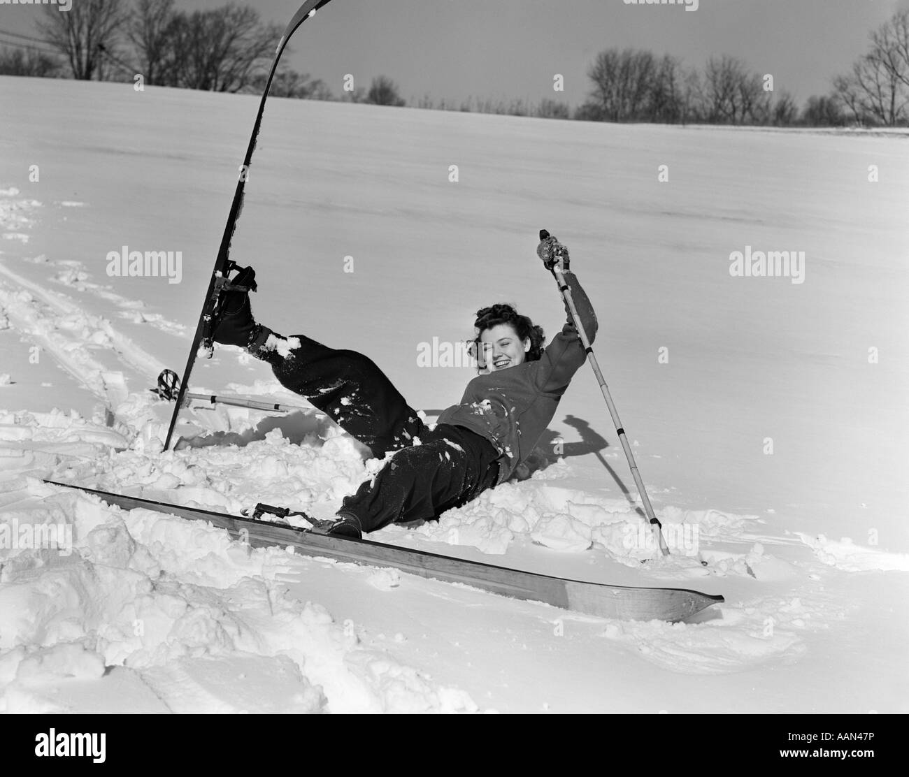 1940s 1930s WOMAN FALLING IN SNOW ON SKIS LAUGHING Stock Photo