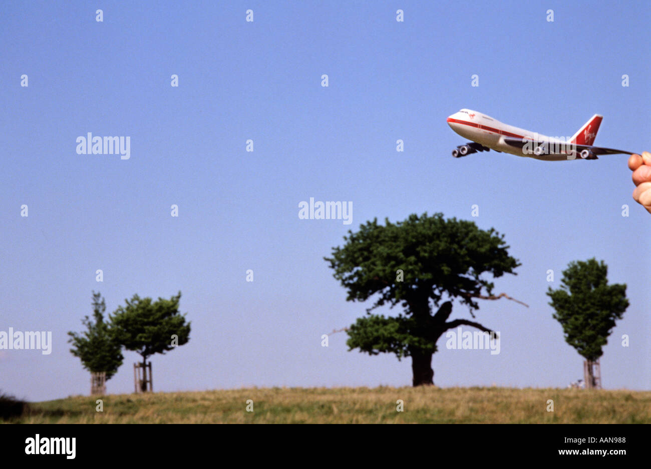 Toy Boeing 747 jumbo jet being held in front of landscape to give appearance of flying Stock Photo