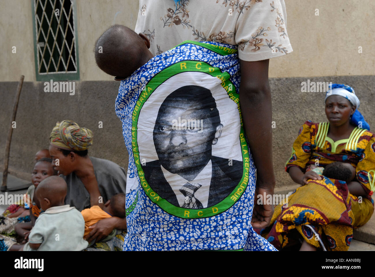 A woman carries a baby on her back using a kitenge bearing the figure of the Congolese President Joseph Kabila Kabange, in North Kivu province, Congo Stock Photo