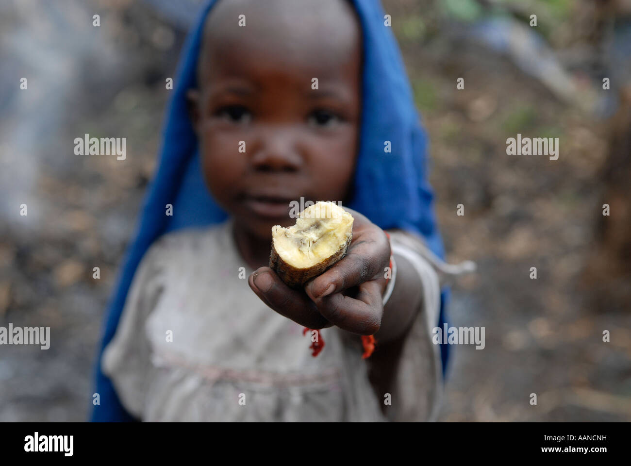 A young child offers a cassava root vegetable in a makeshift IDP camp