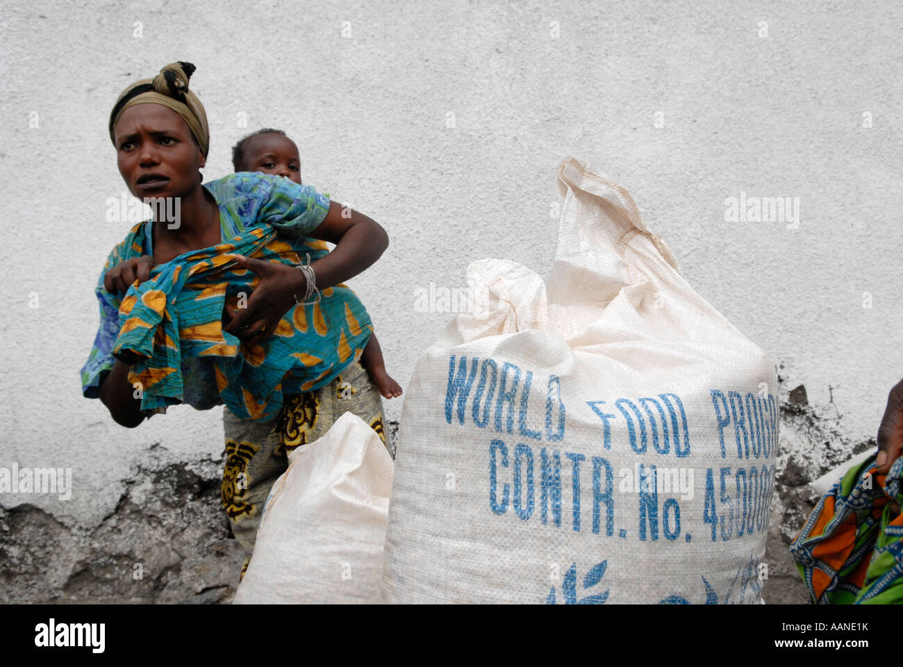 A woman carries a baby on her back during food distribution carried out by the World Food Programme WFP in North Kivu DR Congo Africa Stock Photo