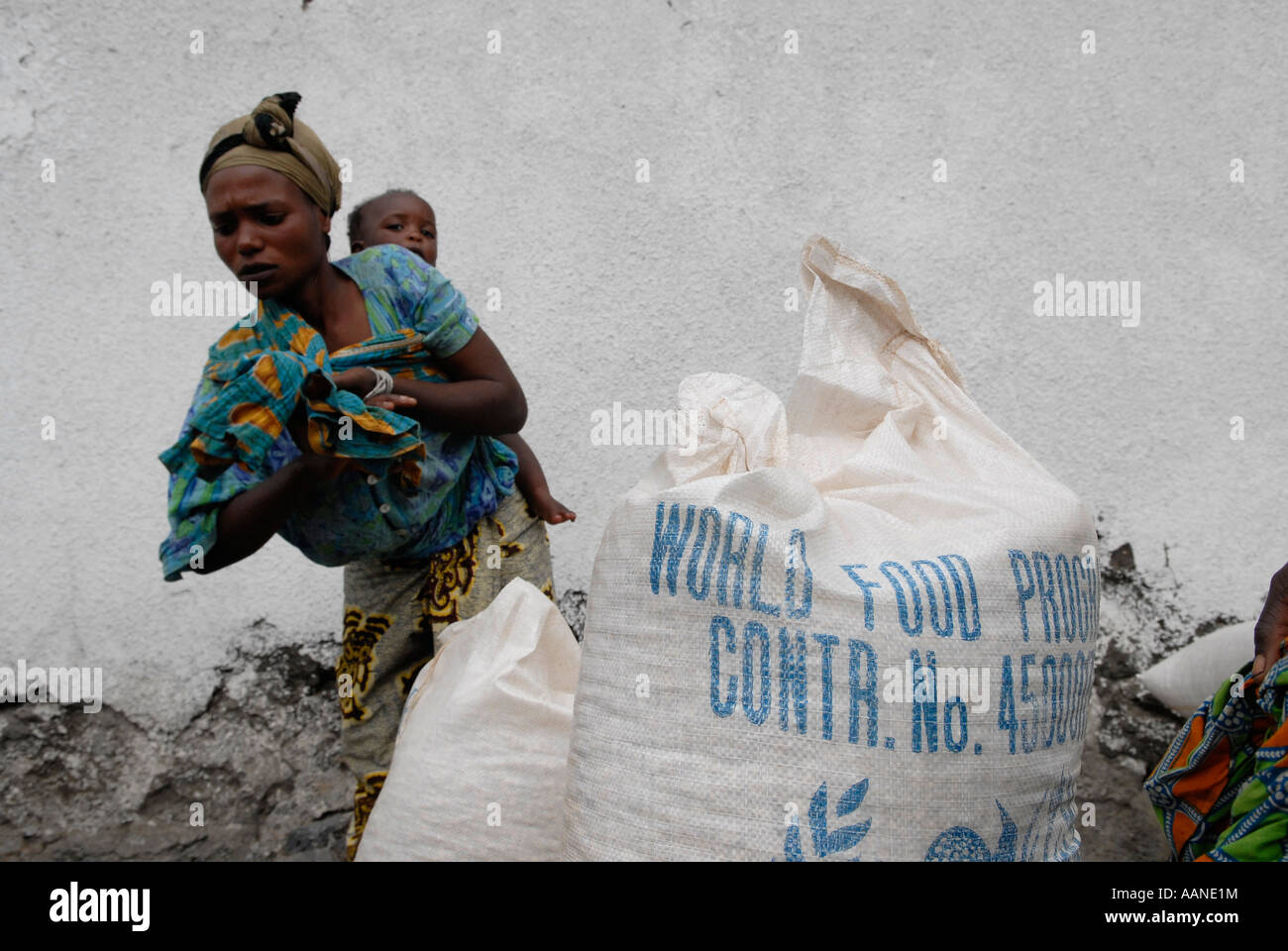 An Internally displaced woman stands next to large sack of corn soya blend during World Food Programme WFP distribution in North Kivu, Congo DR Africa Stock Photo