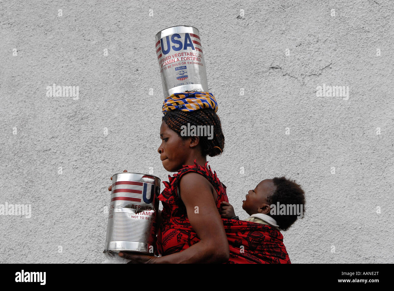 A woman carrying cans of refined vegetable oil donated by USAID during UN World Food Program distribution in North Kivu province, DR Congo Africa Stock Photo