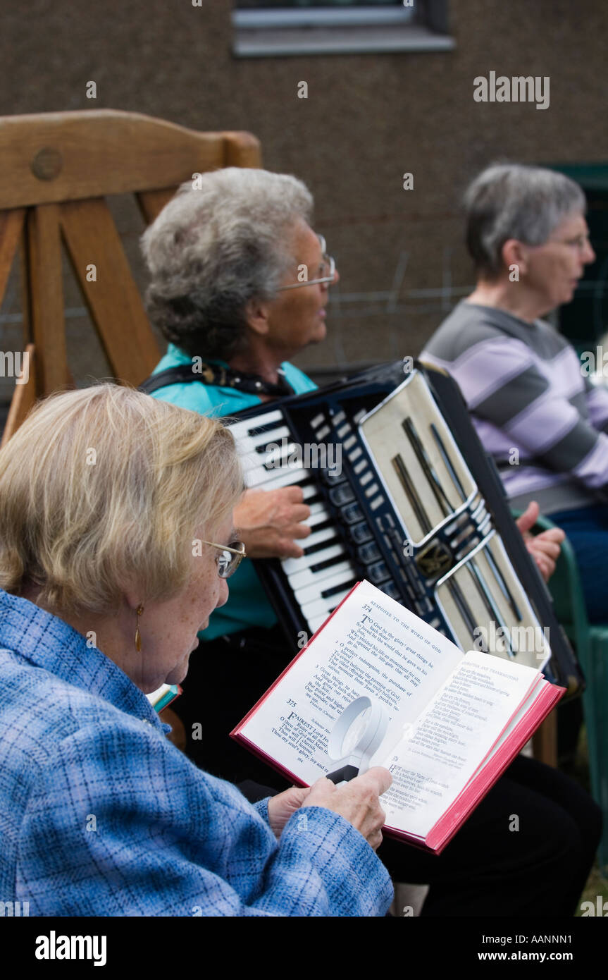 Women singing and playing the accordion at outdoors service. Stock Photo