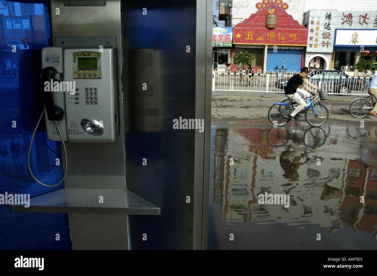 Public phone booth with people riding bicycles in the background, Datong, Shanxi, China. Stock Photo