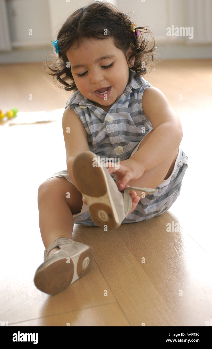 Little girl is putting her shoes on Stock Photo