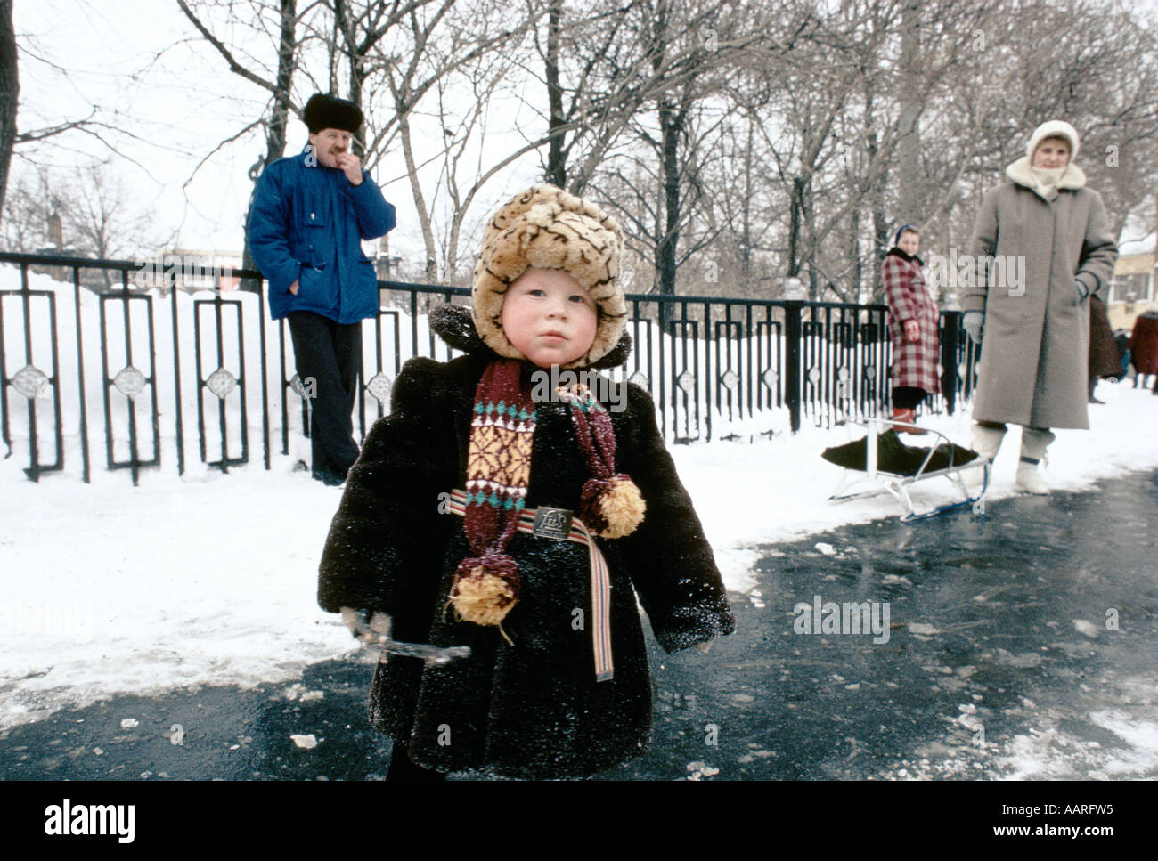 SVERDLOVSK MARCH 1991 YOUNG CHILD ON STREET WOMAN BEHIND WITH SLEDGE  Stock Photo