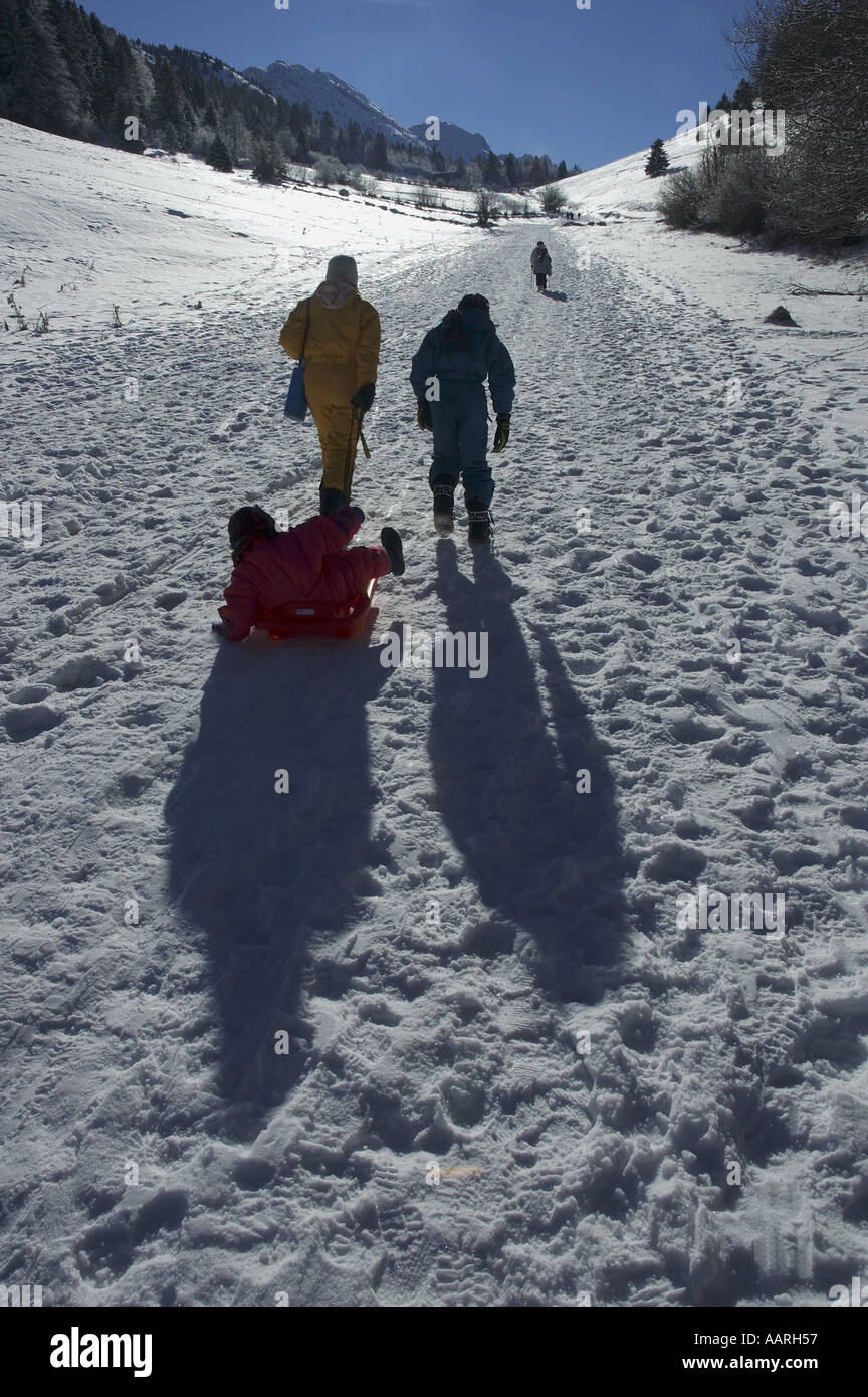 Mother walking with her two kids and a sled along a snowy path Stock ...