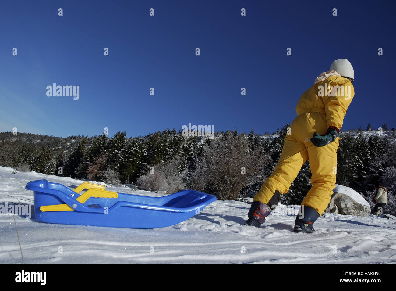 Woman towing a sled behind her in the snow. Stock Photo
