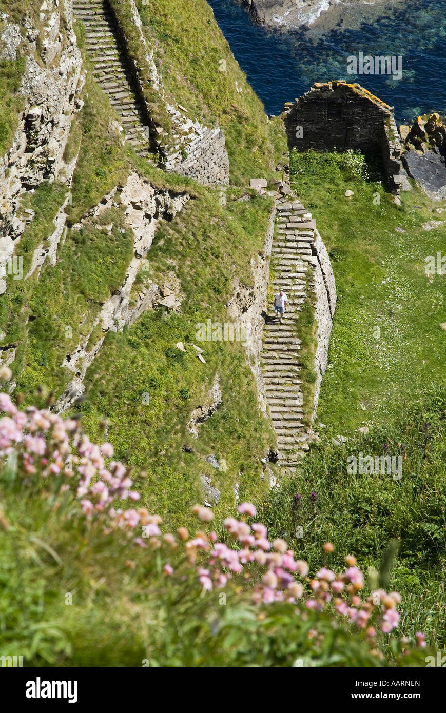 dh  WHALIGOE CAITHNESS Man walking down steep stone steps to cove harbour seacliff scotland coast Stock Photo