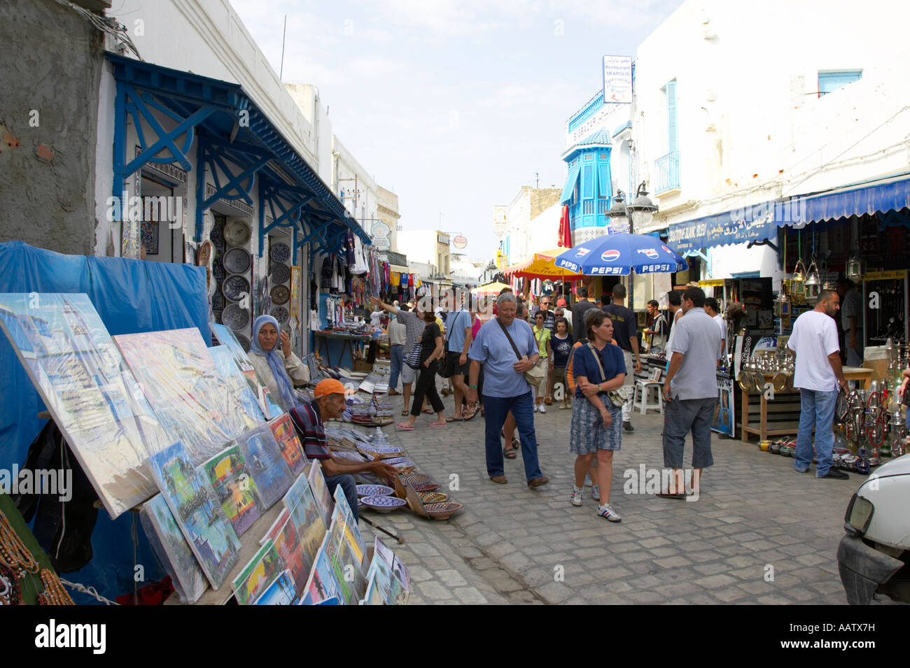 tourists walk up and down past shops and stalls on the narrow cobbled streets of the market at nabeul tunisia Stock Photo