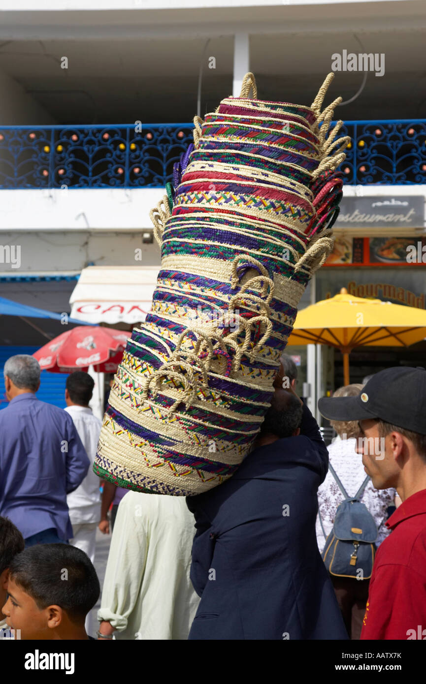 basket maker carries his wares to market through a crowd of people at the nabeul souk Stock Photo
