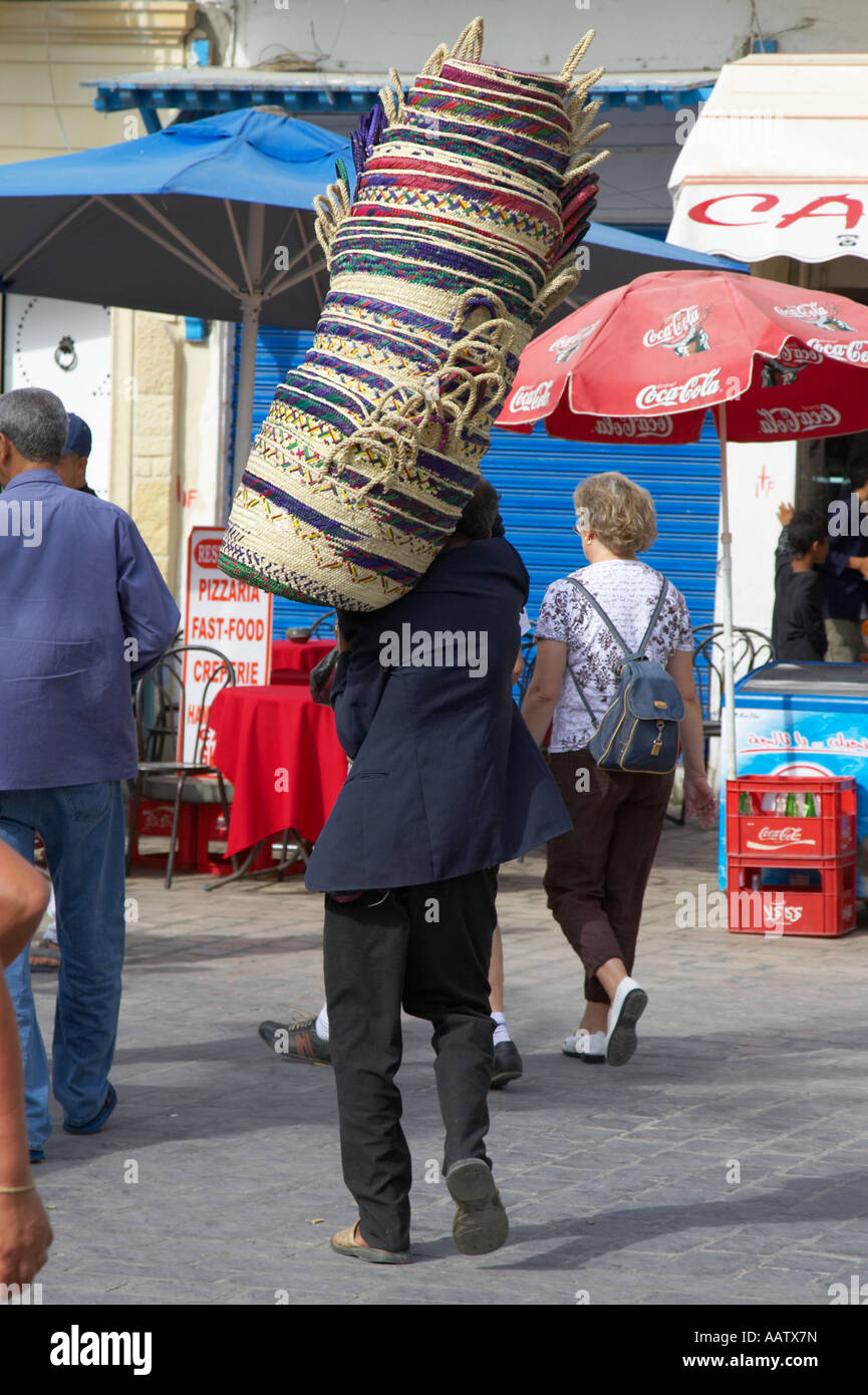 basket maker carries his wares to market through a crowd of people at the nabeul souk Stock Photo