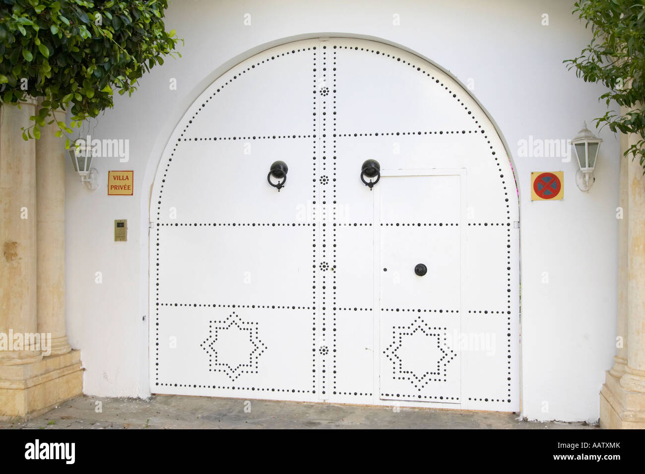 white decorated patterned high security gates at entrance to private house with warning sign hammamet tunisia Stock Photo