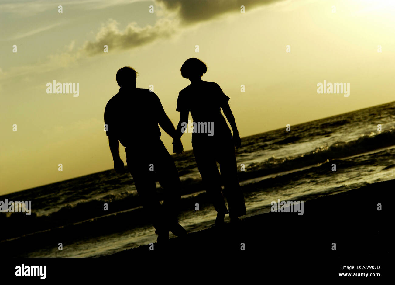 Couple holding hands and walking on beach Stock Photo - Alamy