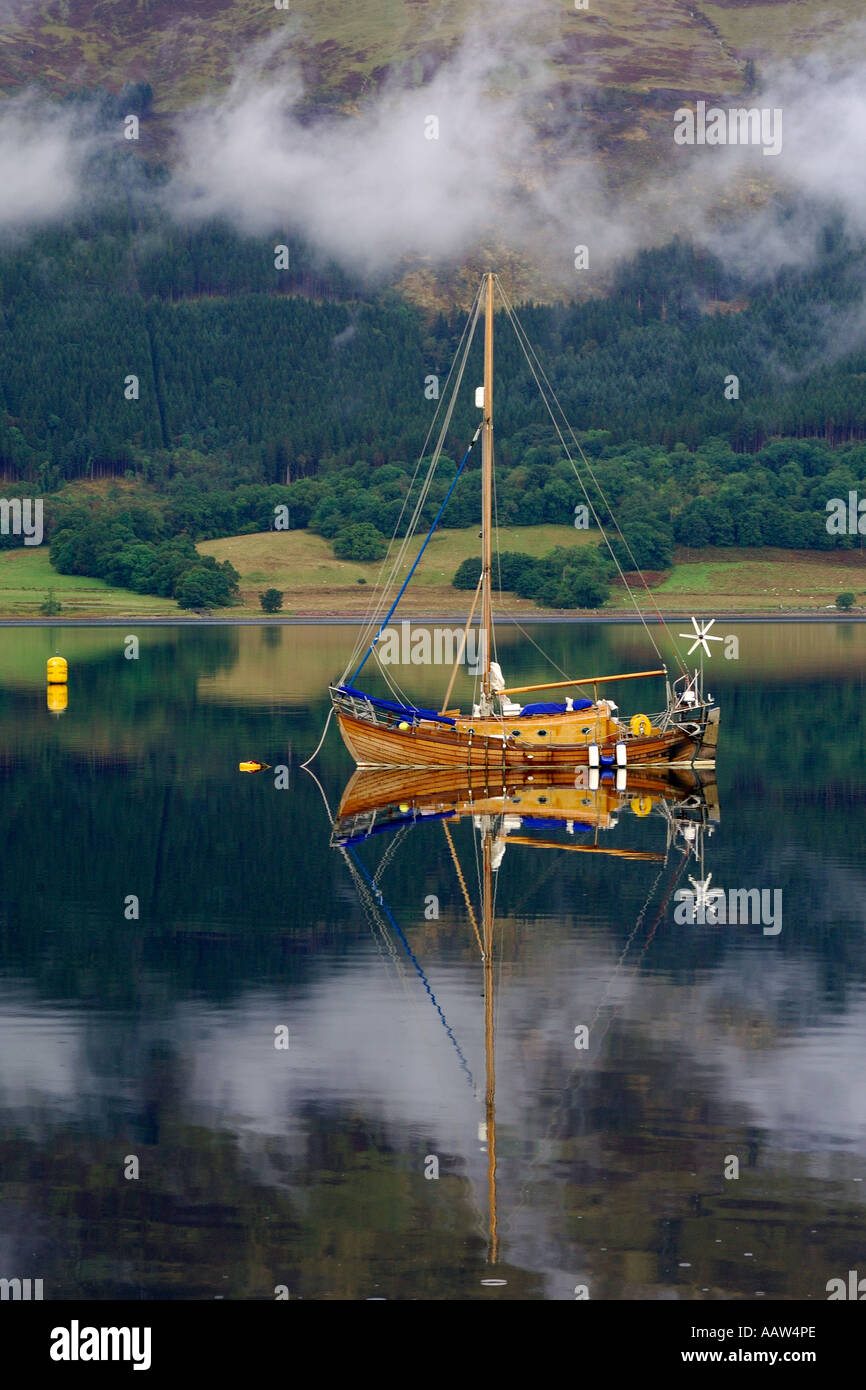 Lovely traditionally built wooden sailing boat moored on Loch Leven near Ballachulish Glencoe with light clouds drifting by Stock Photo