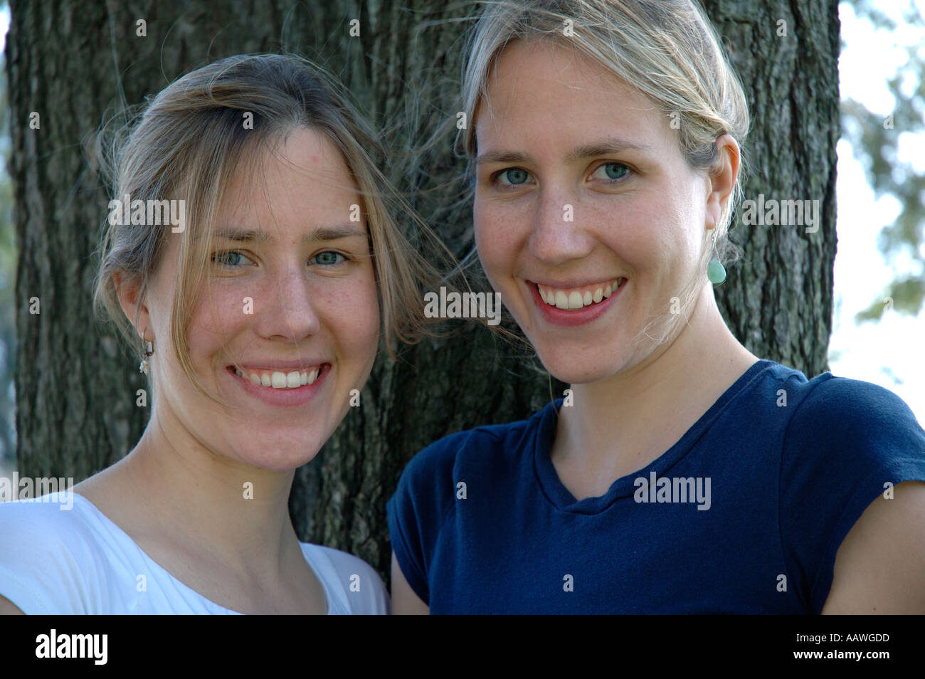 Twin sisters in their early to mid twenties photographed outside in countryside. Stock Photo