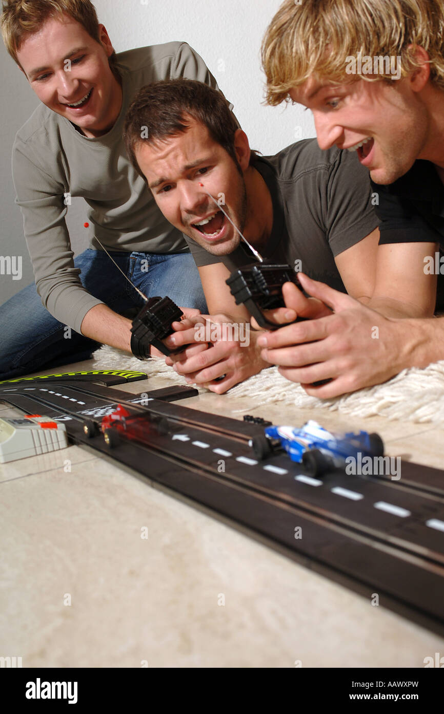 3 young men with Carrera model railway Stock Photo