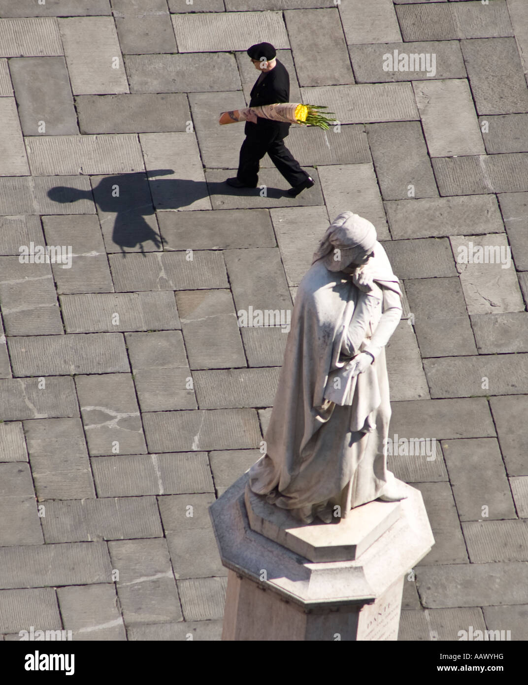 A priest walks through Piazza dei Signori past Dantes statue in Verona Italy with some flowers Stock Photo