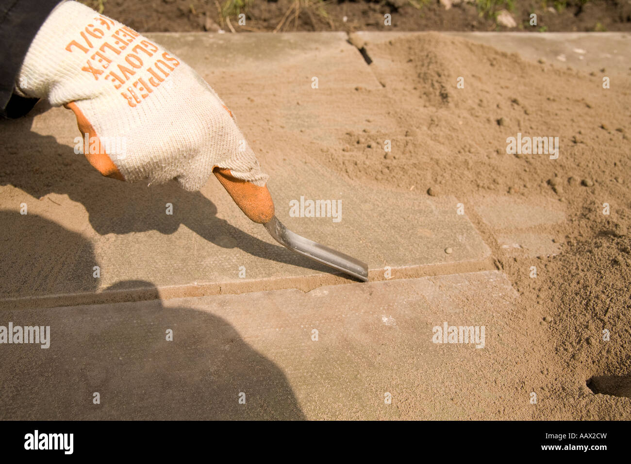 Gloved hand with pointing trowel pointinga mortar joint in a patio