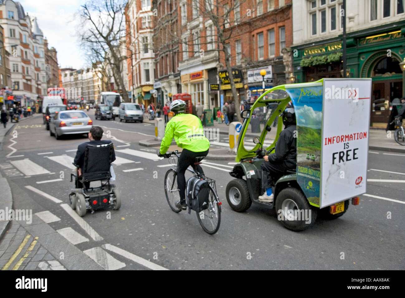 a wheelchair, a bike and a quadbike travel up charing cross road in london Stock Photo