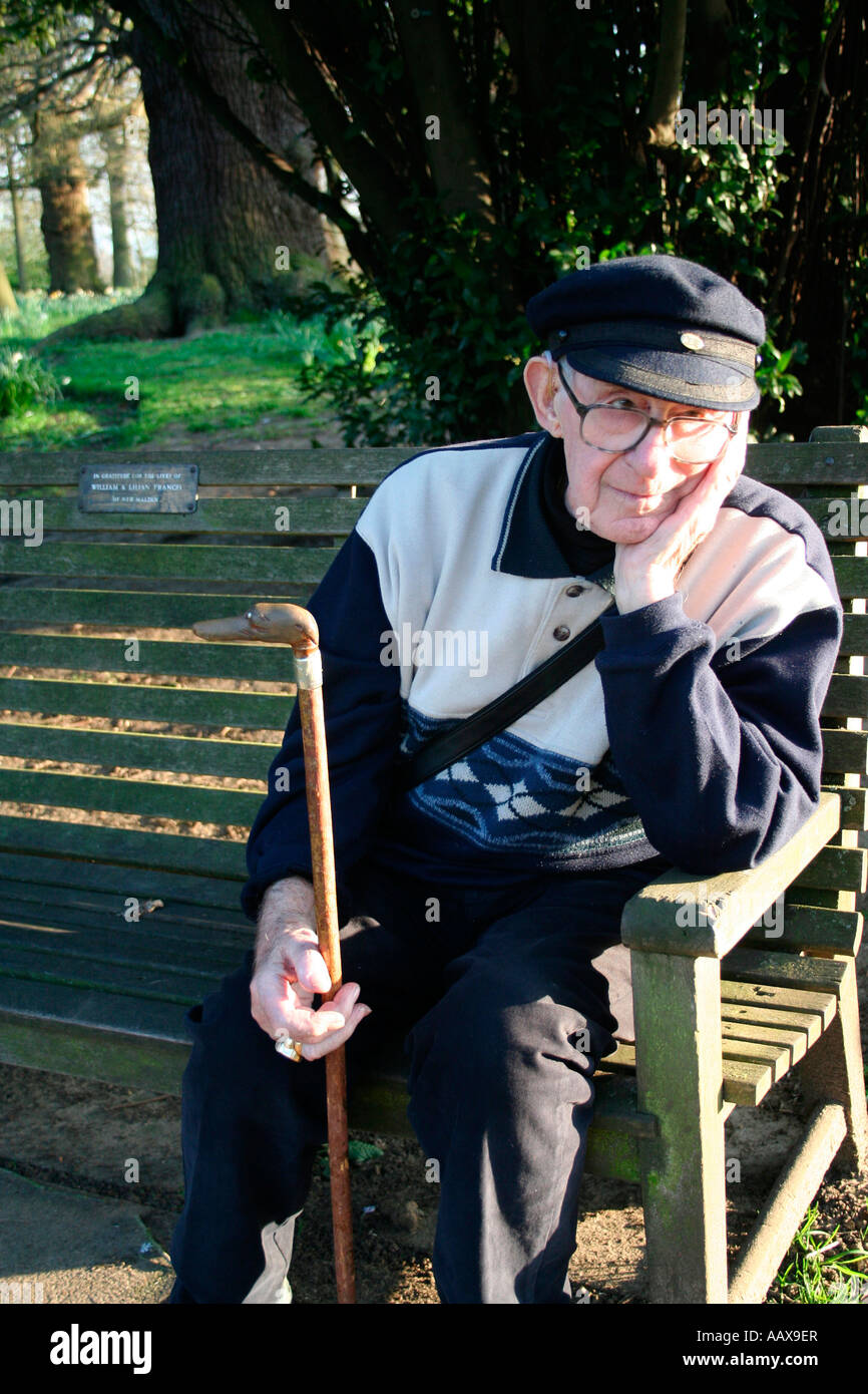 old man sitting on a bench holding a walking stick Stock Photo - Alamy