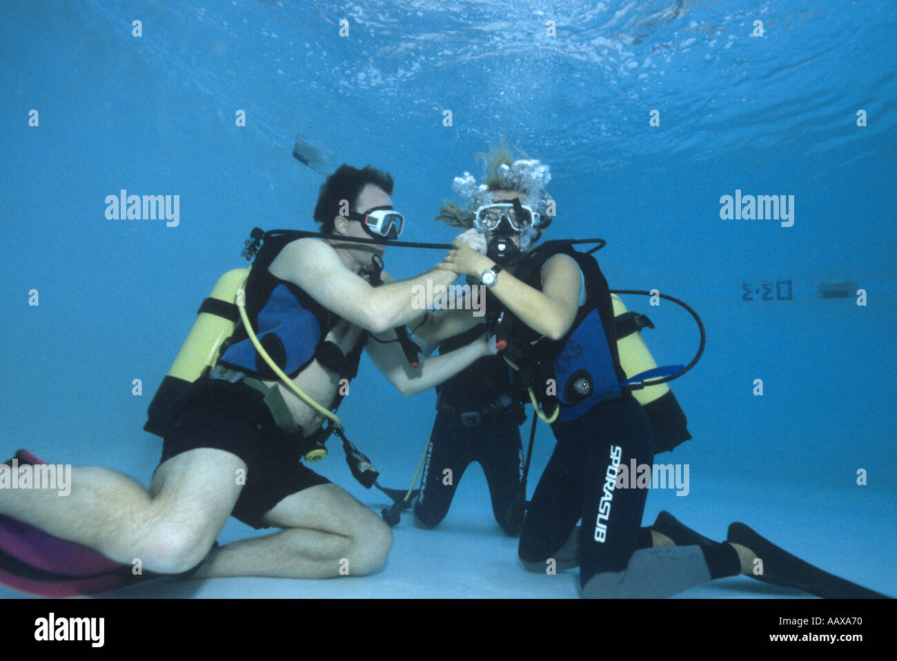 divers practising out of air scenario in swimming pool Stock Photo