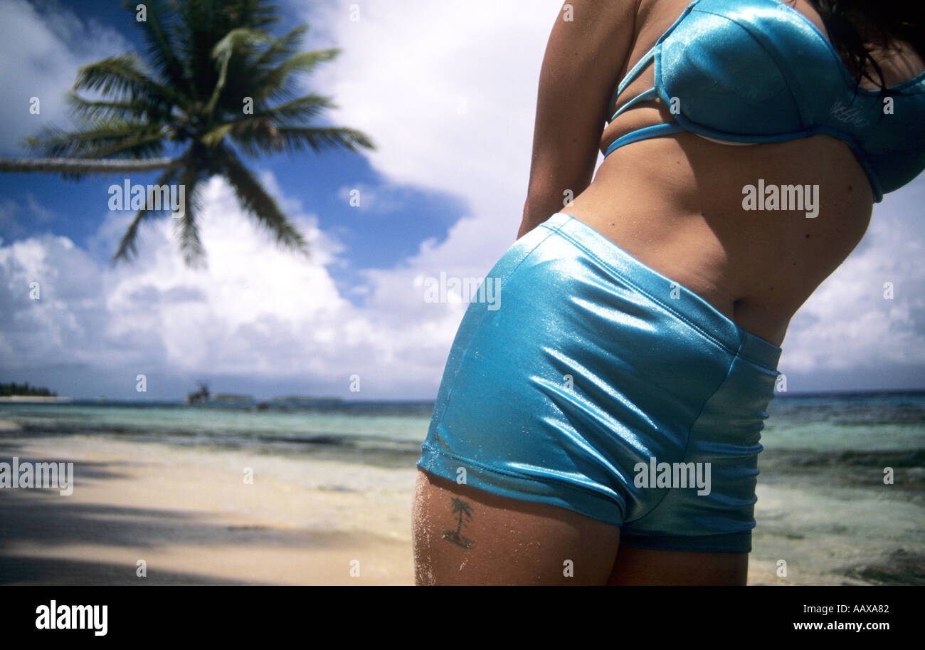 close up view of girl on tropical beach in bikini with palm tree and matching tattoo Stock Photo